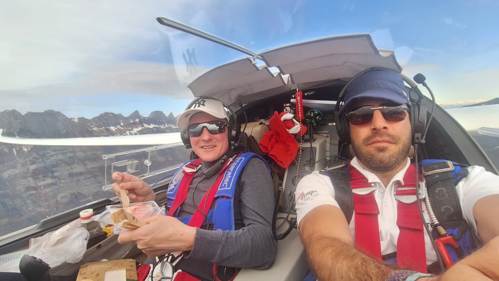 Pilot und Passagier bei einem entspannten Picknick im Flug über schroffen Alpengipfeln
