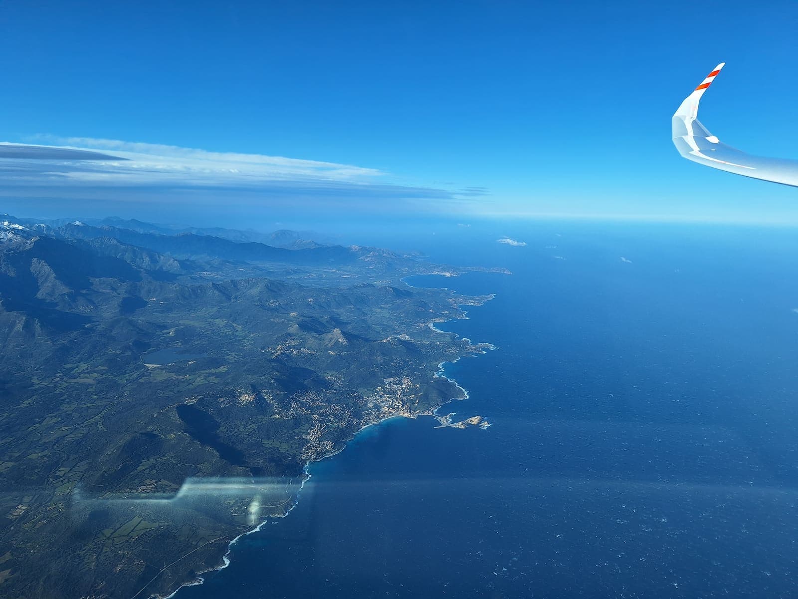 Corsica's mountainous west coast seen from high altitude past the wingtip