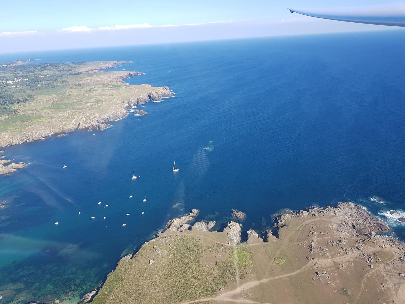 Turquoise coves and anchored boats along the rocky coast of Île-d'Yeu